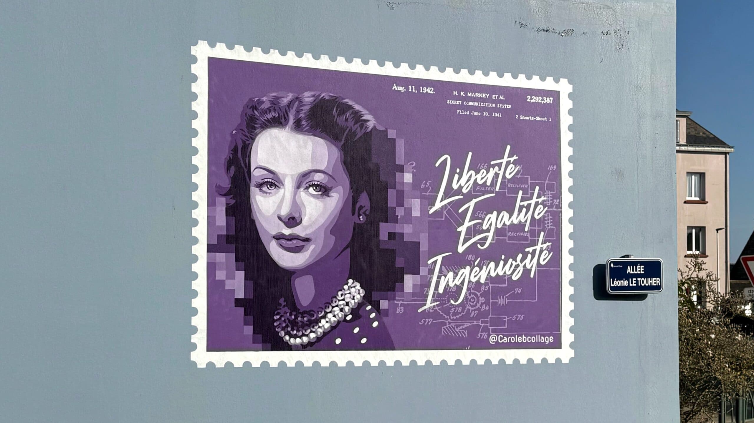 Oeuvre murale représentant le portrait de l'actrice et inventrice Hedy Lamarr sur un fond violet en forme de timbre. Oeuvre réalisée à Larmor-Plage par la street artiste Carole b.